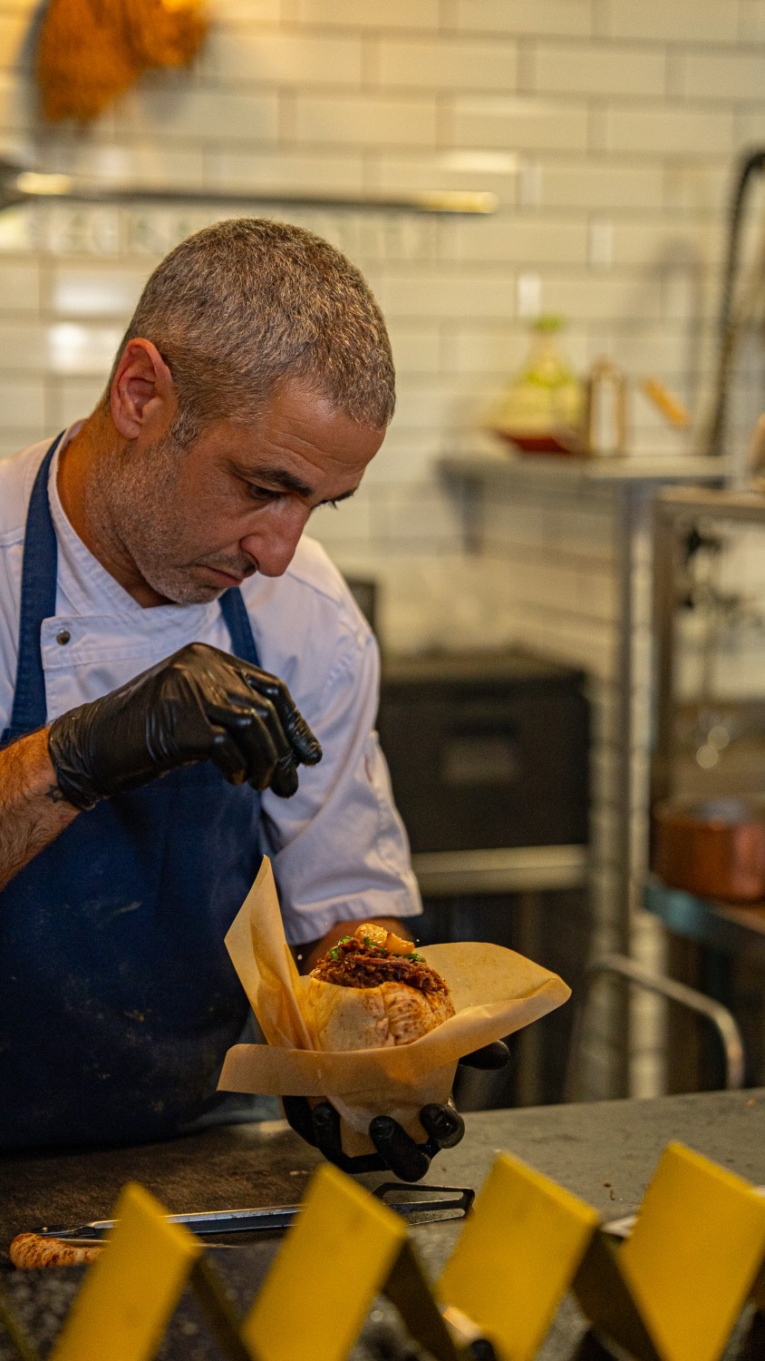 Asaf wrapping a pita in paper