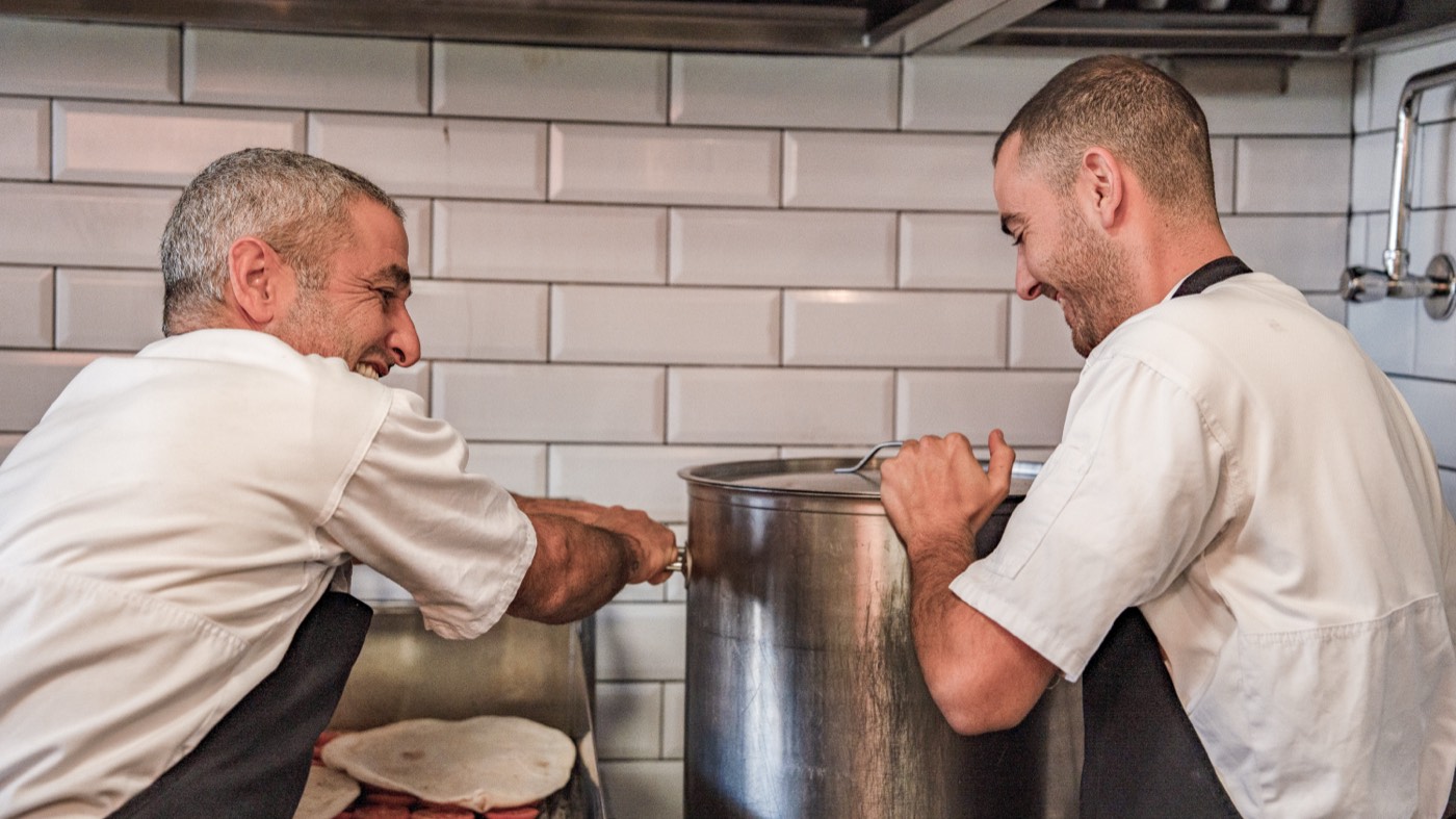 Two cooks laughing over the pot