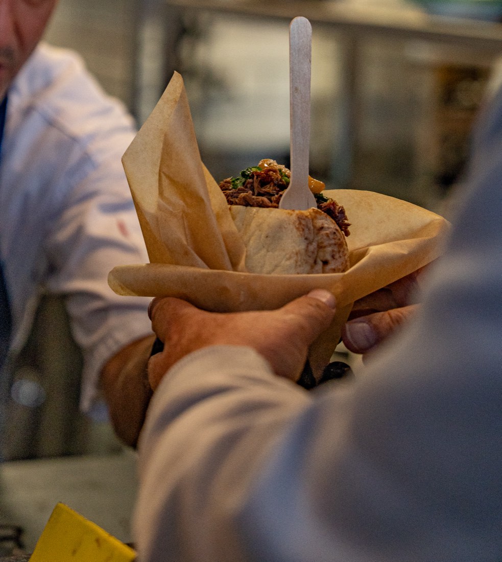 A pita wrapped in paper, in both hands